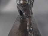 bronze sculpture of a dog on a wooden block