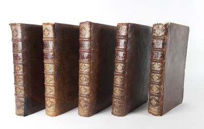 four old books are lined up in a row on a white surface