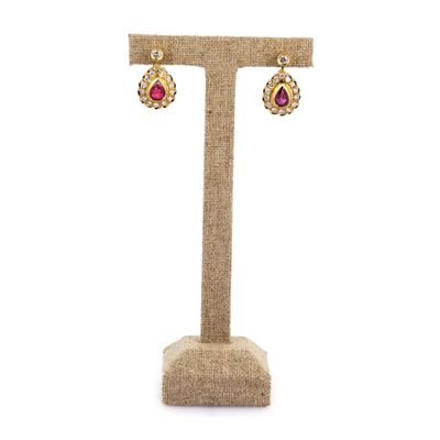 une paire de boucles d'oreilles posée sur un présentoir, sur fond blanc