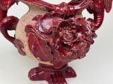 a red vase that is sitting on a white table