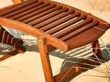 une chaise en bois posée sur le sable de la plage