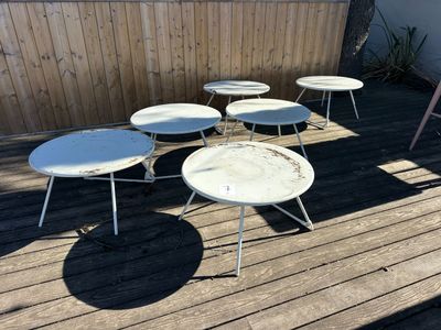 several white tables and chairs on a wooden deck in a backyard