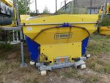 une machine jaune et bleue qui est posée dans l'herbe