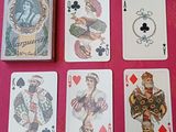 quatre jeux de cartes posés sur une table recouverte d'une nappe rose