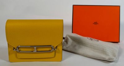 un petit sac à main jaune avec une anse argentée et un tissu