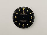 a close up of a black and gold clock on a white wall