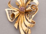an image of a gold brooch with a pink stone center