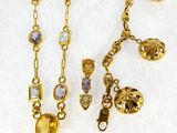 two gold tone necklaces with various colored stones on a white surface
