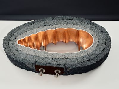 a sculpture made of concrete and copper on a white surface