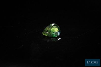 a green tourmaline stone on a black surface