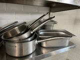 several pots and pans are lined up on a shelf in a kitchen