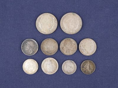 six types différents de pièces d'argent posées sur un tissu bleu