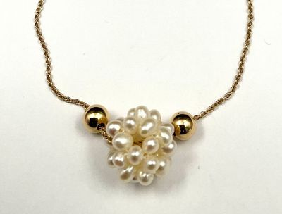 a close up of a necklace with pearls on a chain
