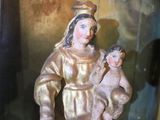 a statue of a woman holding a child in a glass case
