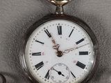 a silver pocket watch with roman numerals on it