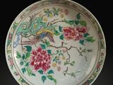 a plate with flowers and birds on it on a black background