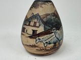 a vase with a picture of a sheep and a house in the background