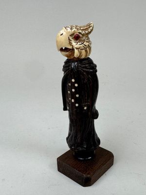 une figurine représentant un homme avec un oiseau sur la tête