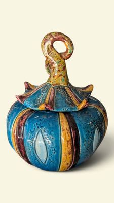 a blue and yellow vase with a bird on top of it