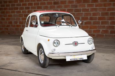a small white car that is parked in front of a brick wall
