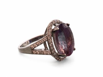 gros plan d'une bague avec une pierre violette entourée de diamants