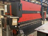 a red and black machine in a warehouse with a large machine in the background