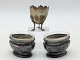 two silver bowls sitting next to each other on a white surface