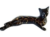 a black cat figurine laying down on a white surface