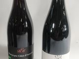 two bottles of red wine sitting next to each other on a table