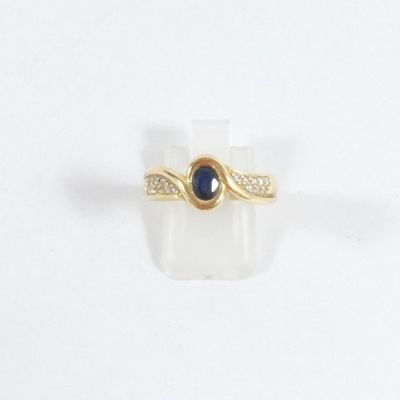 Gros plan sur une bague en or ornée d'une pierre bleue