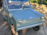 un petit camion vert garé devant un immeuble