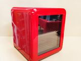 un four à micro-ondes rouge posé sur une table blanche