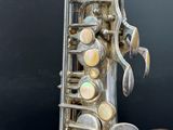 an old silver saxophone sitting on top of a table next to a blackboard