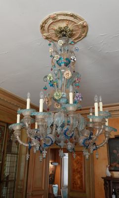 un lustre au milieu d'une pièce où est accroché un tableau au mur