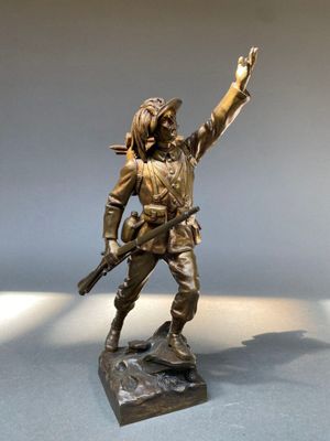 statue en bronze représentant un homme armé, posée sur une surface blanche