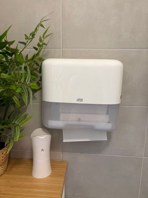 a toilet paper dispenser in the corner of a bathroom
