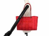 red bag on mannequin stand with black hand holding it