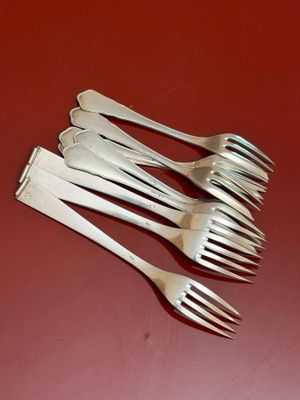 six forks are lined up on a red surface with a red background