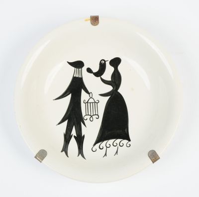 une assiette en noir et blanc sur laquelle est dessiné un homme et une femme tenant une cage à oiseaux