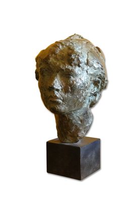 sculpture représentant une tête posée sur un socle en bois, sur fond blanc