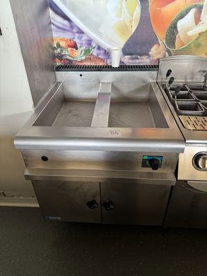 une cuisine équipée d'une cuisinière, d'un évier et d'un tableau accroché au mur