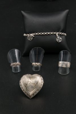 un assortiment de bijoux en argent comprenant un pendentif en forme de cœur, une bague, un bracelet et un étui à bagues