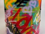 une tasse colorée ornée de graffitis, posée sur une table