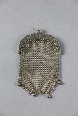 un gros plan d'un sac à main à chaîne argentée posé sur une surface blanche