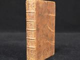 an old book sitting on top of a black cloth covered table