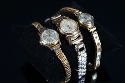 deux montres en or et en argent exposées sur un fond noir