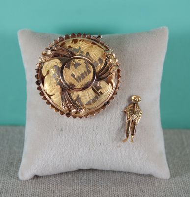 une broche en or et une épingle posées sur un oreiller