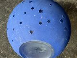 a blue ball with holes on it sitting on the ground