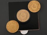 three gold coins sitting on top of a black piece of paper