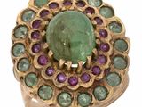une image représentant une bague ornée d'une pierre verte entourée de pierres violettes et vertes